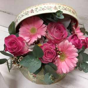 A pretty mixture of pink flowers arranged in a hat box