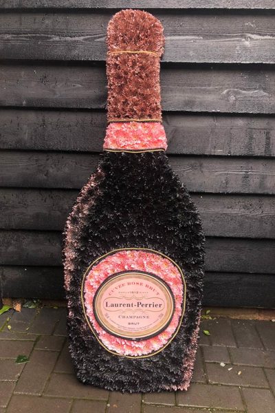 Floral funeral tribute shaped like a bottle of champagne
